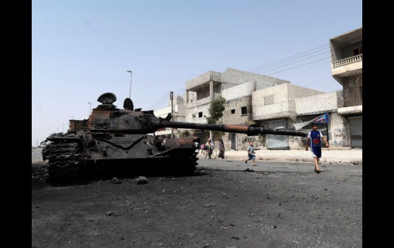 Varios niños juegan cerca a un tanque del ejército sirio destruido tras un enfrentamiento con rebeldes, en una calle de Alepo. EFE  /