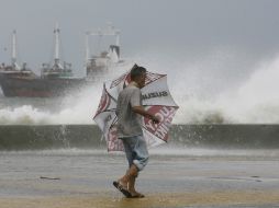 Un hombre camina por la costa mientras las altas olas causadas por el tifón rompen en la orilla. REUTERS  /