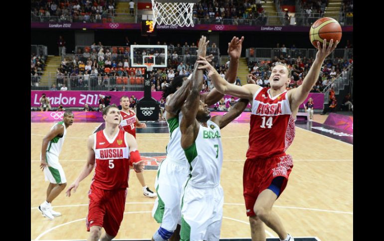 El jugador ruso Anton Ponkrashow inteneta encestar ante los brasileños Larry Taylor Y Nene Hilario. EFE  /