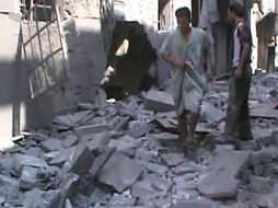 Los hombres caminando sobre los escombros en la calle de una zona residencial de Aleppo. EFE  /