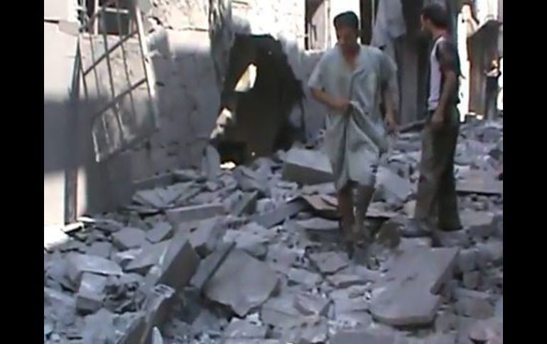 Los hombres caminando sobre los escombros en la calle de una zona residencial de Aleppo. EFE  /