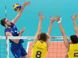 Nikola Kovacevic de Serbia (I) 'pica' a Murilo Endres (C) y Dos Santos Junior durante un bloqueo en el partido del torneo. AFP  /