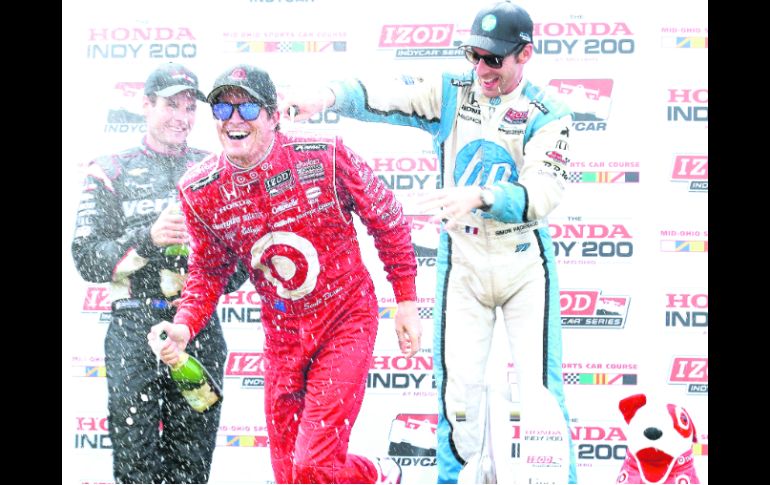 Baño. Scott Dixon recibe la rociada de champaña, por parte de Will Power. AFP  /