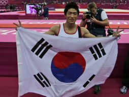 El gimnasta asiático es campeón olímpico de Londres 2012, y lo celebra con la bandera de su nación. AP  /