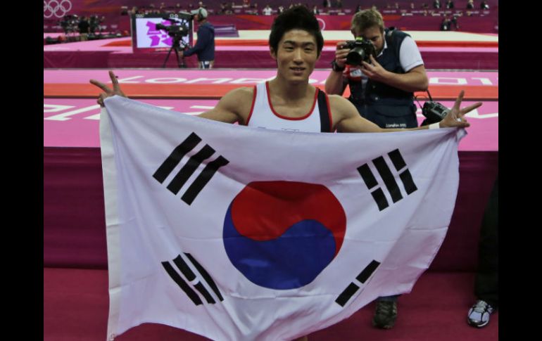 El gimnasta asiático es campeón olímpico de Londres 2012, y lo celebra con la bandera de su nación. AP  /