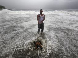 Un hombre pasea con su perro en el mar en República Dominicana, durante el paso de ''Ernesto''. ARCHIVO  /