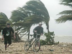 Un ciclista de la playa de Mahuahual, en Quintana Roo, optó por caminar ante las ráfagas del huracán “Ernesto”. REUTERS  /