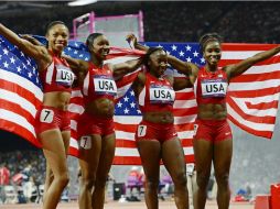 Las atletas celebran con la bandera de estados unidos cubriéndolas. EFE  /