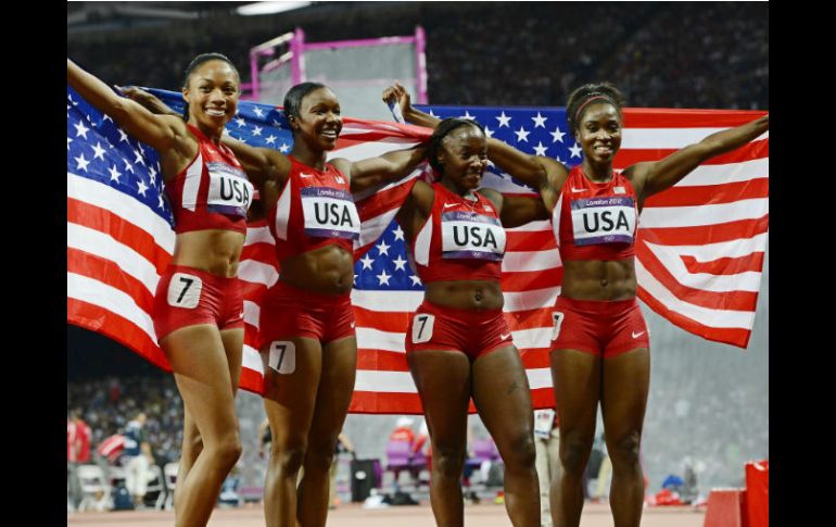 Las atletas celebran con la bandera de estados unidos cubriéndolas. EFE  /