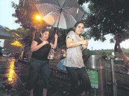 A correr. Dos mujeres buscan refugio de la lluvia registrada la tarde-noche del sábado, en el Centro de Guadalajara.  /