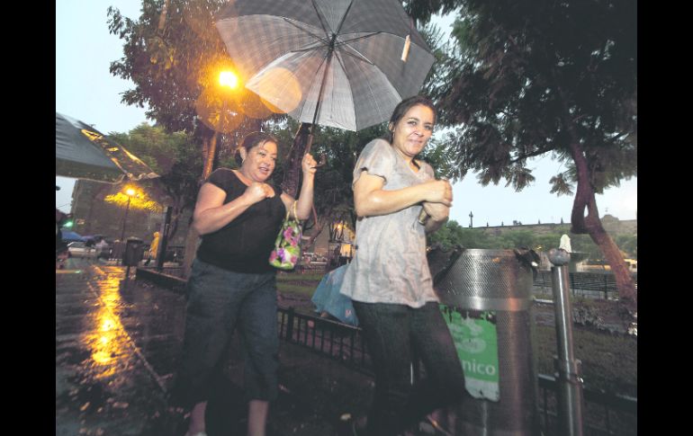 A correr. Dos mujeres buscan refugio de la lluvia registrada la tarde-noche del sábado, en el Centro de Guadalajara.  /