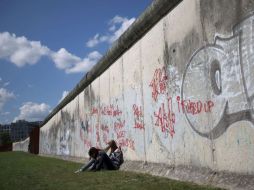 Dos chicas sentadas al lado del muro luego de la ceremonia de colocación de una ofrenda floral en el memorial de Bernauer Strasse. AFP  /