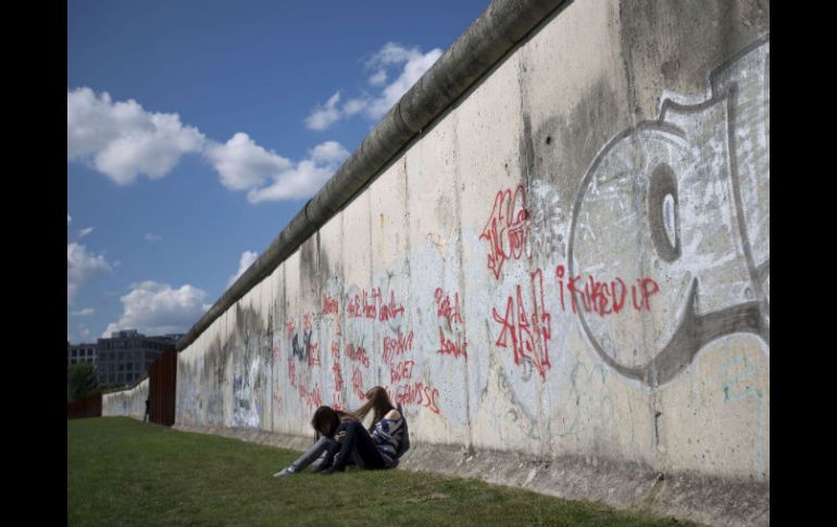 Dos chicas sentadas al lado del muro luego de la ceremonia de colocación de una ofrenda floral en el memorial de Bernauer Strasse. AFP  /