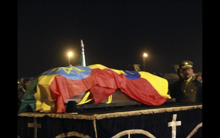 El ataúd, cubierto con la bandera etíope, fue bajado y  montado en un coche en la pista del aeropuerto, con guardia militar. AP  /