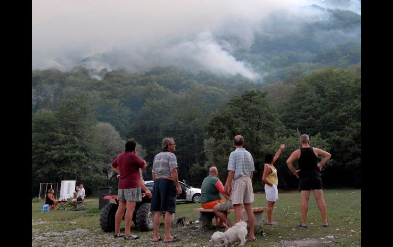 Bosniacoas observan el fuego forestal en el lago Boracko. AP  /