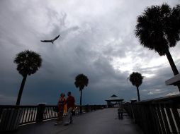 Los visitantes caminan a lo largo del muelle de Clearwater mientras las nubes aumentan la visibilidad de la tormenta en  Florida. AFP  /