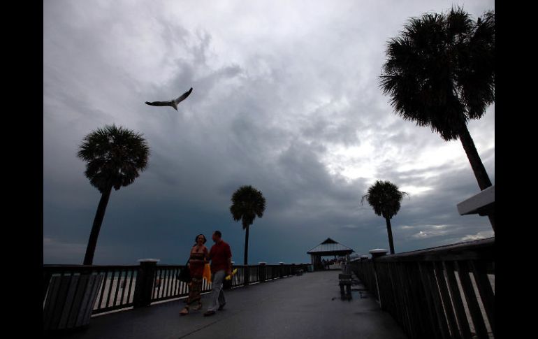 Los visitantes caminan a lo largo del muelle de Clearwater mientras las nubes aumentan la visibilidad de la tormenta en  Florida. AFP  /