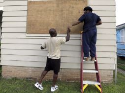 Vecinos aseguran las ventanas de sus casas en Nueva Orleans, previniendo la llegada de Isaac. AP  /