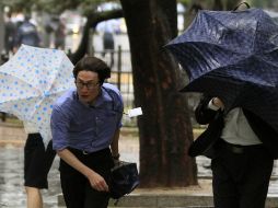 Ciudadanos de Seúl luchan contra los vientos huracanos del tifón para llegar a sus destinos. AP  /