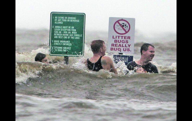 Contra el consejo de las autoridades tres jóvenes y un menor se divierten en las aguas del lago Pontchartrain, en Louisiana. AP  /