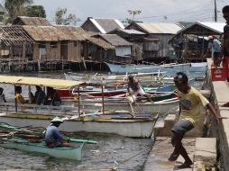 Los filipinos vuelven a sus botes en una aldea de pescadores, tras retirarse la alerta. EFE  /