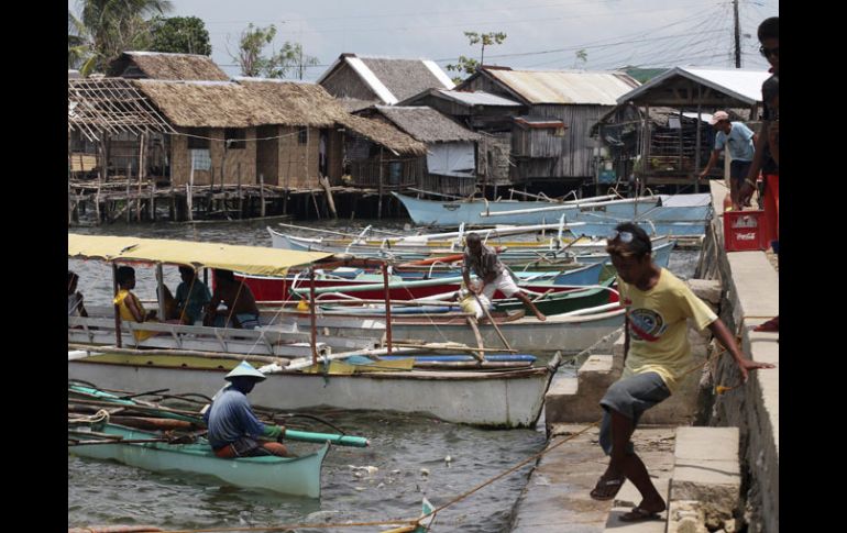 Los filipinos vuelven a sus botes en una aldea de pescadores, tras retirarse la alerta. EFE  /