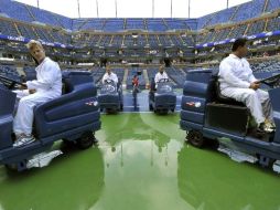 Operarios laboran a nivel de cancha para secar la superficie previo al arranque de la semifinal masculina. AFP  /