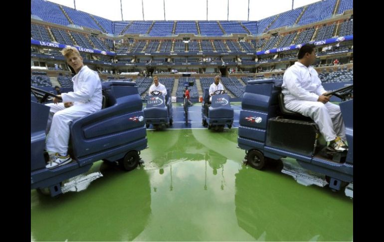 Operarios laboran a nivel de cancha para secar la superficie previo al arranque de la semifinal masculina. AFP  /