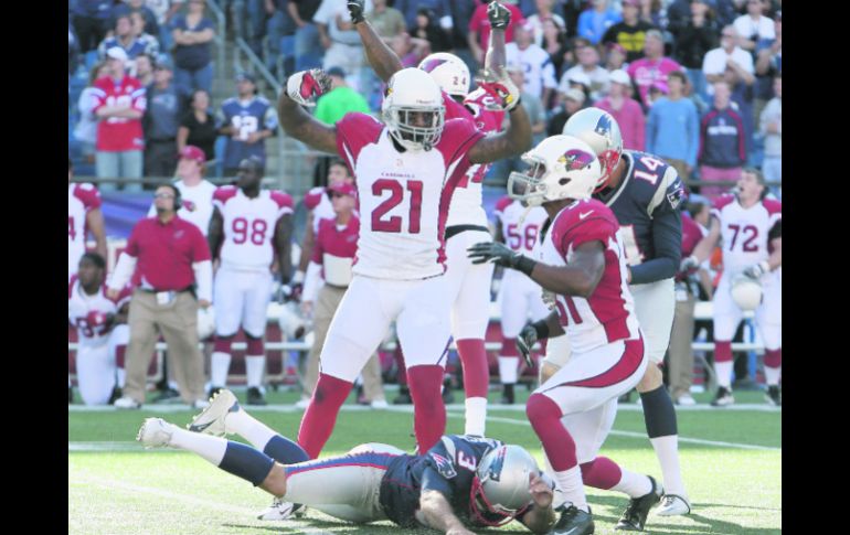 Stephen Gostkowski yace en el terreno, tras fallar su patada, mientras los jugadores de Arizona celebran la victoria en patio ajeno. AP  /