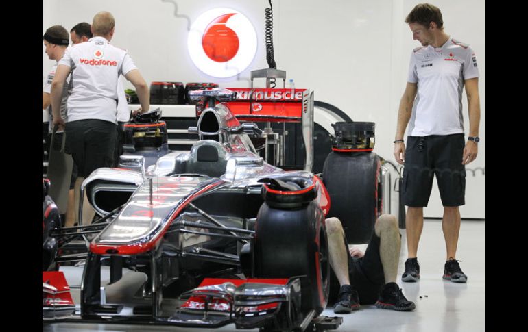 Jenson Button (der) observa la preparación de su auto por parte de los mecánicos de McLarren. AP  /