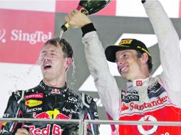 Baño que sabe a gloria. Jenson Button rocía de champaña a Sebatian Vettel, durante la ceremonia de premiación. AP  /