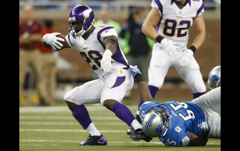 Adrian Peterson corre ante la fuerte defensiva de Detroit. AP  /