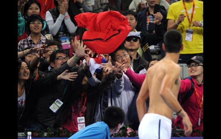 El serbio, Novak Djokovic, arroja su playera a sus fans luego del partido de semifinal en el Abierto de China. AFP  /