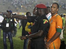 Didier Drogba es protegido por un policía de Senegal el pasado domingo durante los disturbios en Dakar. AP  /