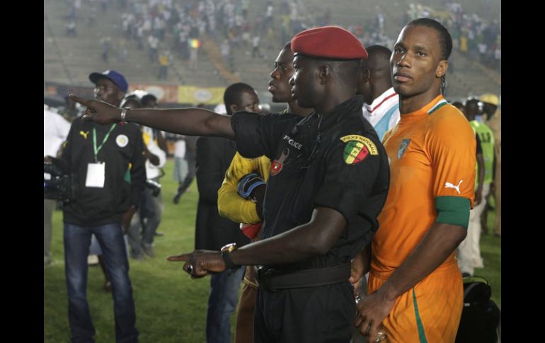 Didier Drogba es protegido por un policía de Senegal el pasado domingo durante los disturbios en Dakar. AP  /