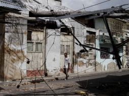 Un hombre camina en una calle en la que las instalaciones de luz fueron dañadas por los fuertes vientos de ''Sandy''. AP  /