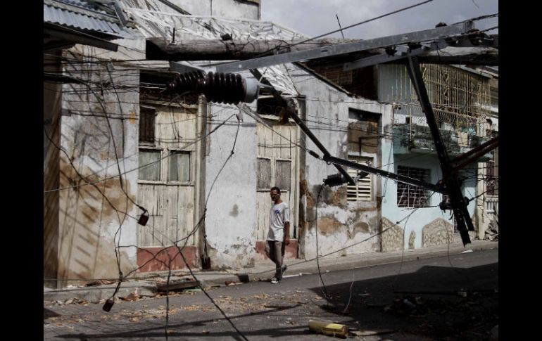 Un hombre camina en una calle en la que las instalaciones de luz fueron dañadas por los fuertes vientos de ''Sandy''. AP  /