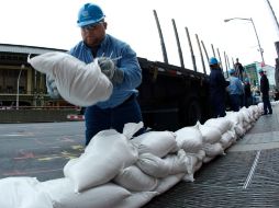 Trabajadores en Nueva York colocan sacos de arena para cubrir bóvedas de energía previo a la llegada de 'Sandy'. REUTERS  /