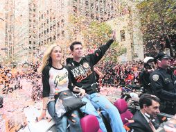 Héroe. El catcher Buster Posey saluda a la gente durante el desfile, acompañado por su esposa Kristen. AFP  /