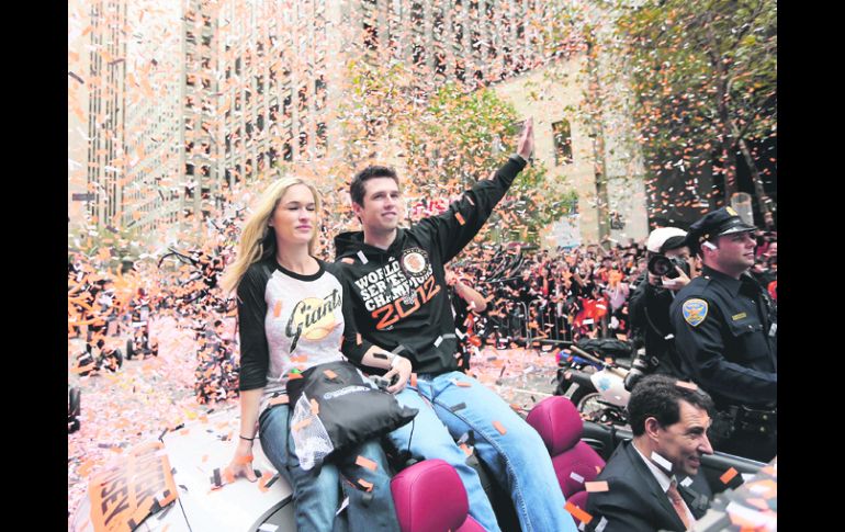 Héroe. El catcher Buster Posey saluda a la gente durante el desfile, acompañado por su esposa Kristen. AFP  /