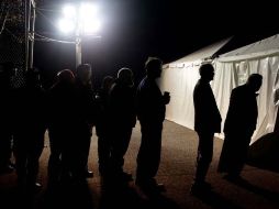 Bajo la luz de un generador eléctrico, votantes esperan fuera de una tienda para votar en Staten Island, Nueva York. AP  /