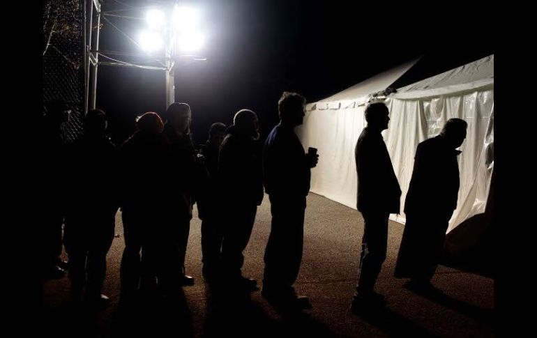 Bajo la luz de un generador eléctrico, votantes esperan fuera de una tienda para votar en Staten Island, Nueva York. AP  /