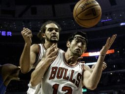 Kirk Hinrich (12) intenta salvar un balón ante Joakim Noah. AP  /