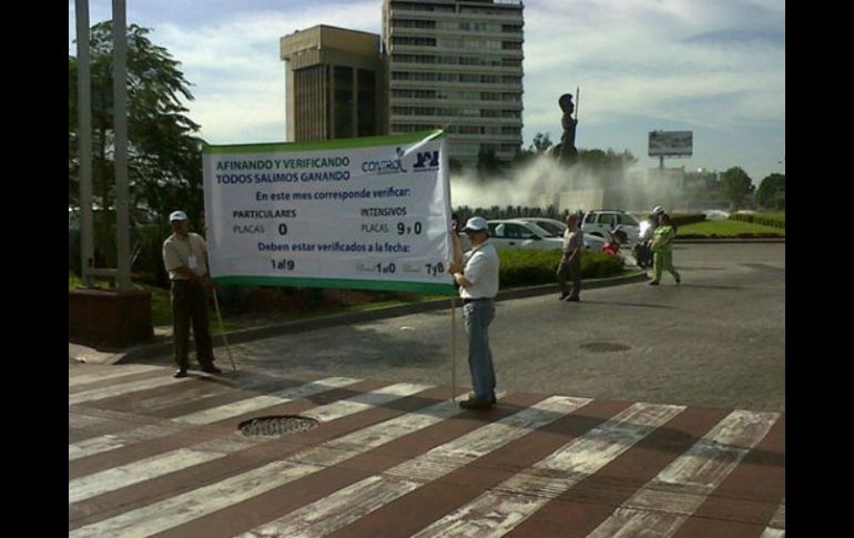 Personas con pancartas promueven la verificación vehicular, en calles que confluyen con la Glorieta Minerva.  /