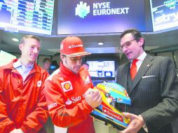 En la chamba. Fernando Alonso firma un casco para uno de sus patrocinadores, durante una visita a la Bolsa de Valores en Nueva York.EFE  /