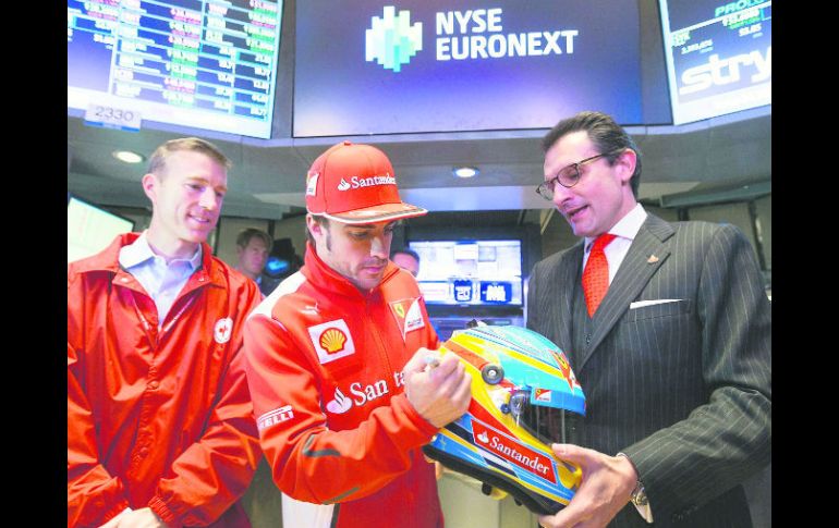 En la chamba. Fernando Alonso firma un casco para uno de sus patrocinadores, durante una visita a la Bolsa de Valores en Nueva York.EFE  /