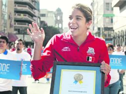 Feliz. Alejandra Orozco presume su galardón, mientras saluda a la gente que acudió a la ruta del desfile.  /