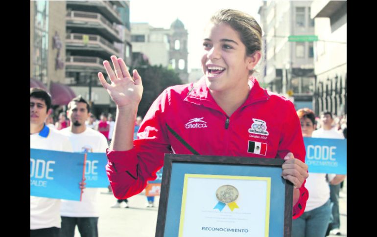 Feliz. Alejandra Orozco presume su galardón, mientras saluda a la gente que acudió a la ruta del desfile.  /