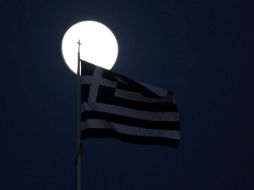 Una bandera de Grecia frente a la luz de la luna en Atenas. REUTERS  /