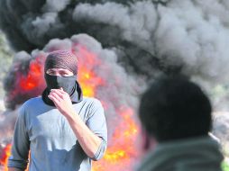 Palestinos queman neumáticos en una manifestación en contra de las expropiaciones de tierras por parte de Israel en Cisjordania. AFP  /